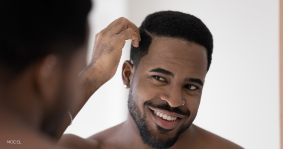 African American man looking in mirror and touching hair